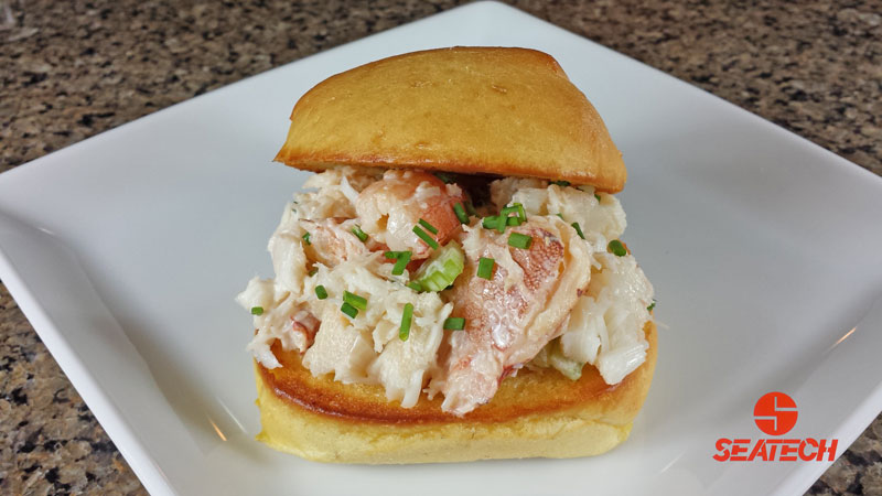 A photograph of a Chilean crab Meat slider with crab, mayonnaise, seasoning salt and chives on a grilled roll.