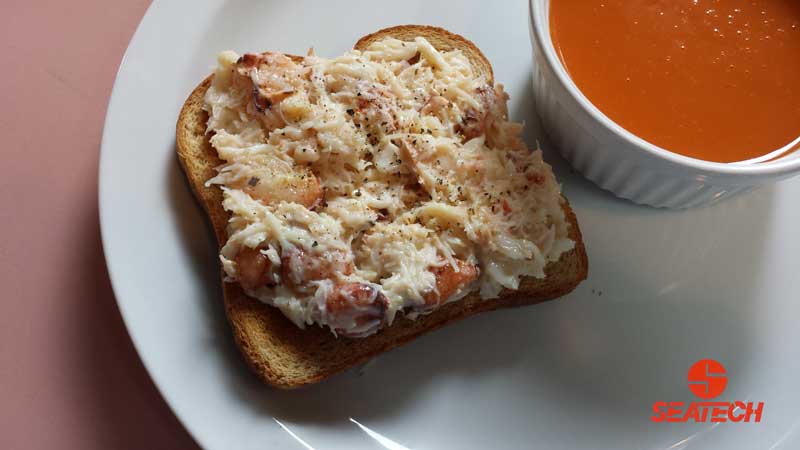A photograph of chilean crab salad on toast with a cup of tomato soup.