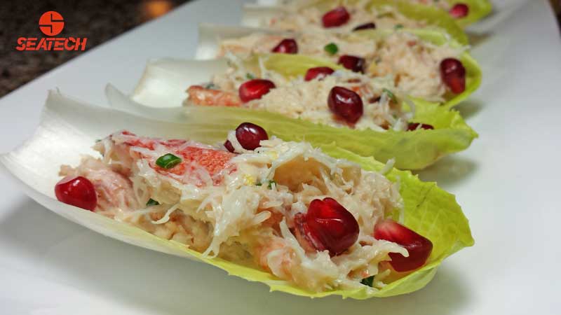 A photograph of crab salad on endive leaves with pomegranate.