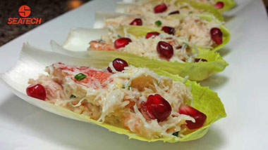 A photograph of Chilean crab salad on endive with pomegranate.