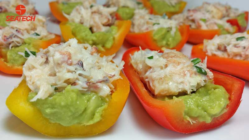 A photograph of crab stuffed mini sweet peppers with crab salad and avocado.