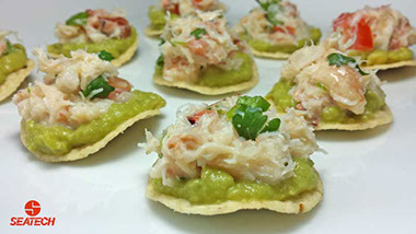 A photograph of mini crab tostada appetizers with crab meat, avocado, cilantro, onion, mayonnaise and lime juice.